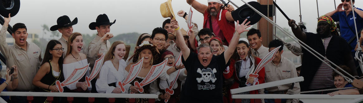 Showing a group of Buc Days Leadership Program winners posing with paper swords on a boat.
