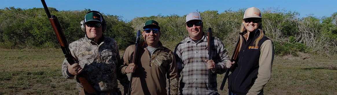 Showing a group of four people holding shotguns.