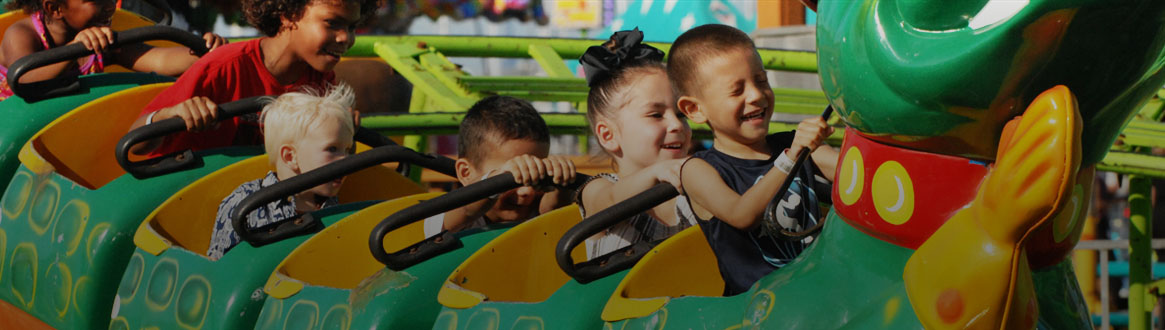 Showing a group of young children riding carnival rides.