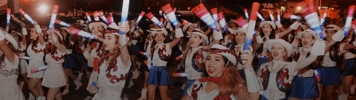 Showing some women wearing cowboy hats while holding some light sticks marching in the Night Parade.